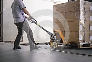 Warehouse worker unloading cargo pallet out of the inside container truck. Shipment boxes. Delivery service.