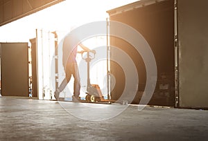 Warehouse Worker Unloading Package Boxes Out of The Inside Cargo Container. Truck Parked Loading at Dock Warehouse.