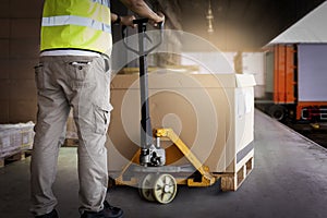 Warehouse worker working with hand pallet truck loading heavy boxes on pallet into cargo container. Shipment, Delivery sevice.