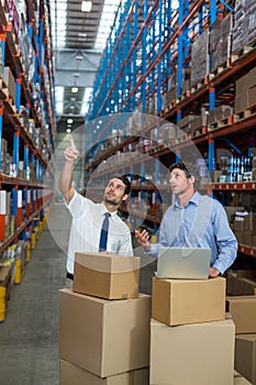 Warehouse workers discussing with laptop