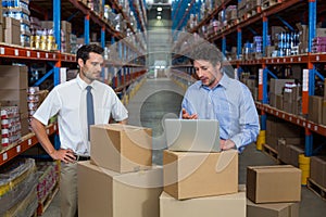 Warehouse workers discussing with laptop