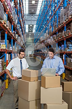 Warehouse workers discussing with laptop