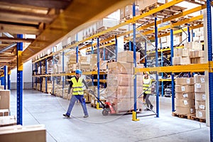 Warehouse workers pulling a pallet truck.