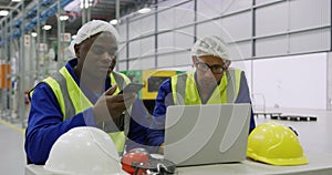 Warehouse workers using laptop in factory