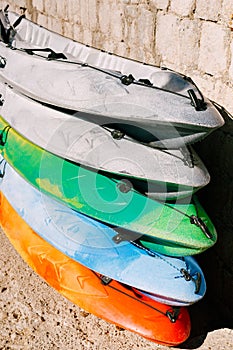 A warehouse of yellow, blue, green, grey kayaks on shore. Single kayaks. Rental kayakshop store on sandy beach