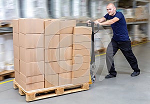 Warehouseman in storehouse fast-moving pallet with stacker. Worker in warehouse moves pallet in rack system.