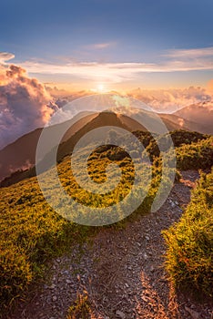 Warm afternoon sun setting down over the clouds in warm colors on a hiking path from the top of HeHuanShan in Taiwan
