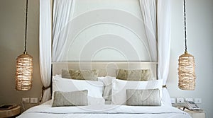 Warm atmosphere around bedroom in resort style hotel with white bedsheet, set of pillows on bed