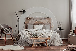 Warm bedroom interior with king size bed with wooden headboard with light, fury blanket
