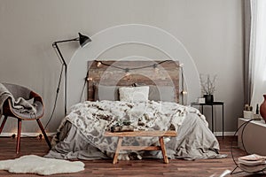 Warm bedroom interior with king size bed with wooden headboard with light, fury blanket photo