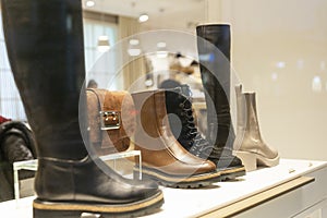 Warm boots and shoes in a shop window. Seasonal footwear, new collection