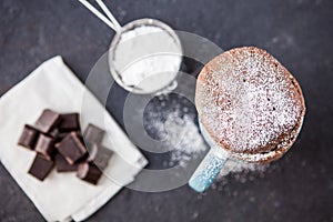 Warm chocolate cake in a mug sprinkled with icing sugar