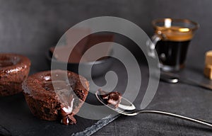 Warm chocolate lava cake on a black plate with a cup of coffee on a dark background