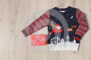 Warm Christmas sweater and gift box on light  table, flat lay