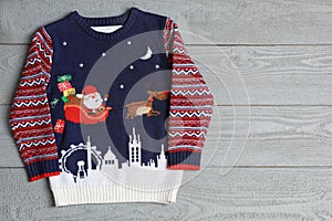 Warm Christmas sweater on grey table, top view. Space for text