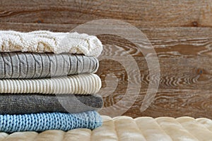 Warm clothing lies in a pile on a fluffy soft rug. Knitted sweaters on a wooden background. Autumn and winter concept