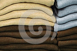 Warm clothing neatly folded on a store shelf. Sweatshirts, sweaters, jumpers, cardigans, hoodies, bobmers with piles on the shelf