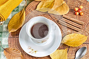 warm coffee in cup on table decorated with autumn leaves and wood