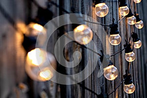 Warm color LED light bulbs on old wooden background in the garden, copyspace, outdoor lighting deciration concept