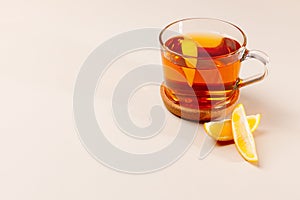 Warm composition with glass cup of black tea with lemon slice inside.