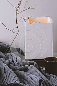 Warm and cosy home with cup of coffee, concrete lampe and rustic wool plaid photo
