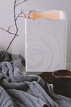 Warm and cosy home with cup of coffee, concrete lampe and rustic wool plaid photo