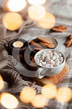 Warm cozy bedroom interior with cup of hot chocolate on tray, candles christmas lights