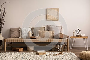 Warm and cozy composition of meditation living room interior with mock up poster frame, couch, beige carpet, pillows, coffee table