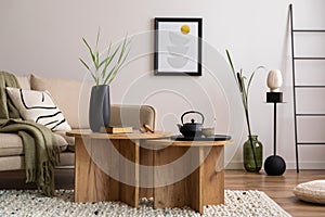 Warm and cozy interior of living room with beige sofa with pillow, round wooden coffee table, geometric small table. Home decor.