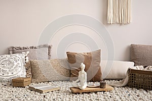 Warm and cozy interior of meditation living room interior with copy space, armchair, beige carpet, plaid and personal accessories