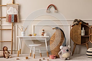 Warm and cozy kids room interior with white desk, stool, animal wicker basket, rattan sideboard, stylish toys, plush monkey, koala