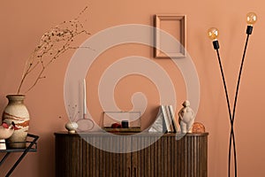 Warm and cozy living room interior with frame, wooden commode, ladder, round coffee table vase with dried flowers, sculpture,