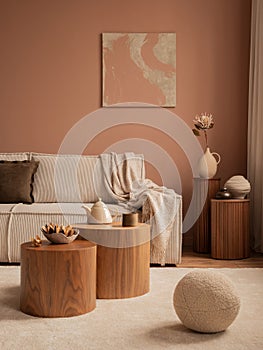 Warm and cozy living room interior with mock up poster frame, modular sofa, round wooden coffee table, pitcher, plaid, vase with