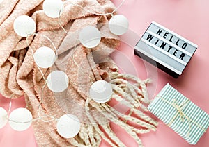 Warm, cozy winter scarf, lightbox on pastel pink background. Christmas, New Year concept flat lay.