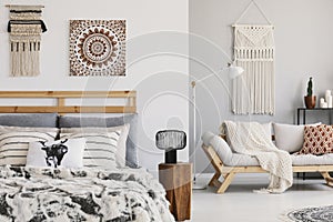 Warm ethno bedroom with patterned pillows on the bed and couch and macrame on the wall