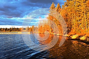 Warm evening sunlight bathes the shoreline of Waskusiu Lake