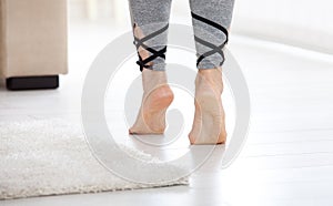 Warm floor concept. Closeup of female legs stepping by hardwood floor at home