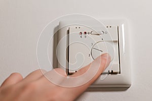 Warm floors switch. Heating control in the house.Heating the house with warm floors.Hand close-up turns on the floor