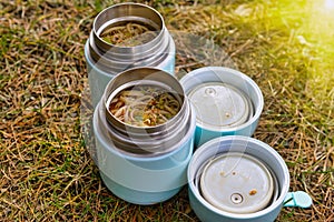 Warm food in a thermos standing on the grass