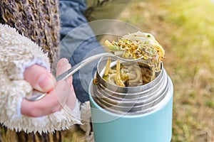 Warm food in a thermos standing on the grass