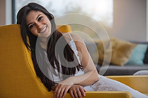 Warm friendly sincere portrait of a likable and genuine mixed ethnicity Indian woman at home relaxing on the sofa