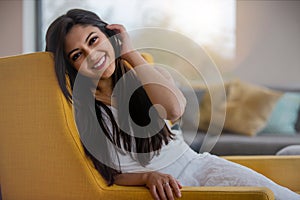 Warm friendly sincere portrait of a likable and genuine mixed ethnicity Indian woman at home relaxing on the sofa