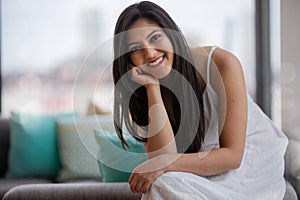 Warm friendly sincere portrait of a likable and genuine mixed ethnicity Indian woman at home relaxing on the sofa