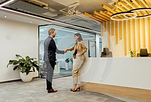 Warm Handshake Between Colleagues In Modern Office Lobby Under Ambient Lighting