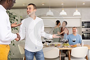 Warm handshake from host to friend at home dinner event