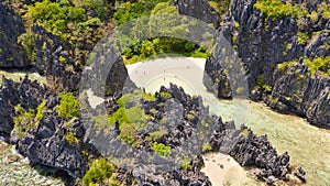 Warm hidden lagoon near the rocks. Tourists relax on the white beach. Tourist routes in the Philippines.