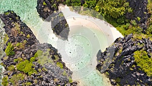 Warm hidden lagoon near the rocks. Tourists relax on the white beach. Tourist routes in the Philippines.