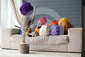 Warm interior with merino wool balls in multicolour on white sofa and on decorative tree