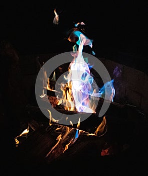 Warm, inviting fire burning in a hearth on a dark night, the flames dancing in a variety of colors