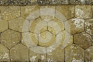 Warm toned closed up of historic honey combed shaped stone wall in Sicily Italy